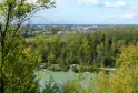 Vista panorâmica do Parque da Ermida Santa Catarina em Bordéus com um lago em primeiro plano, floresta de choupos e horizonte da cidade sob céu nublado